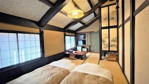 A traditional Japanese-style room with tatami flooring, a low ceiling with exposed beams, a sliding door, and a bed with white bedding. - Gozoku no Yakata Daitoen (Chino)