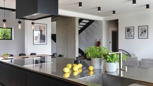 A modern kitchen with a central island, black pendant lights, and a staircase leading to another level. - Villa Polei with Pool (Pula)