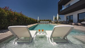 A pool area with two lounge chairs and two glasses of orange drink. - Villa Polei with Pool (Pula)