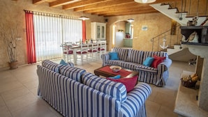 A spacious living area with striped sofas, a dining table, and a staircase leading to an upper level. - Holiday Home Tranquil with Pool (Krnica)