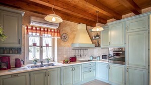 A kitchen with light green cabinets, a wooden ceiling, and a window with red curtains. - Holiday Home Tranquil with Pool (Krnica)