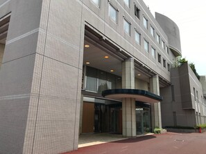 A modern building with a tiled facade, large windows, and a curved entrance. - Business Hotel Noda (Noda)
