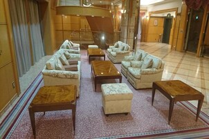 Un hall de hotel con varios sofás, una mesa de centro y una alfombra estampada.