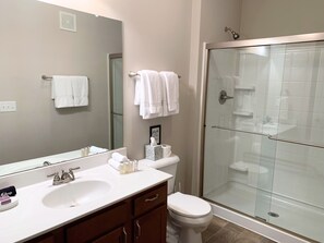 Ein modernes Badezimmer mit einer begehbaren Glasdusche, einem weißen Waschbecken und einer Toilette.