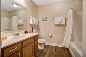 A bathroom with a sink, mirror, toilet, and shower.