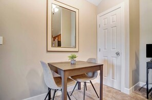 A dining area with a wooden table, two chairs, a potted plant, and a white door.