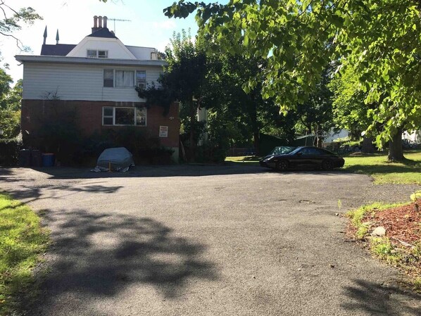 Une maison à deux étages avec un garage, un abri-voiture couvert et une allée.