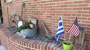 Pared de maó amb un contenidor metàl·lic que conté una roda de bicicleta, una bandera i una planta en test.