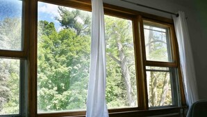 Una habitació amb una finestra gran que dona a una zona boscosa.