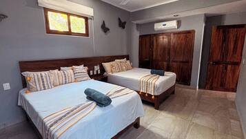 A bedroom with two beds, a ceiling fan, a window with blinds, and a wardrobe.