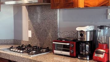 A kitchen with a gas stove, a toaster oven, a coffee maker, and a blender.