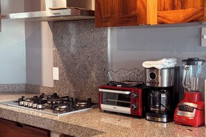 A kitchen with a gas stove, a toaster oven, a coffee maker, and a blender.