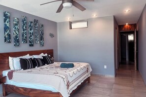 A bedroom with a wooden bed, a ceiling fan, and a wall-mounted light.