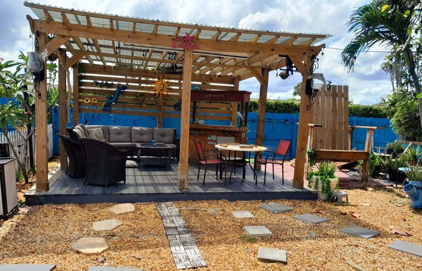 Eine überdachte Terrasse im Freien mit einer Holz-Pergola, einer Couch, einem Esstisch und Stühlen.