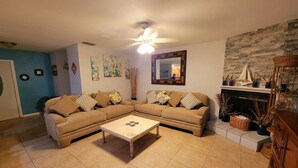 A living room with a sectional sofa, a coffee table, a fireplace, and a stone wall.