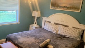 A bedroom with a bed, a nightstand, a lamp, and a painting on the wall.