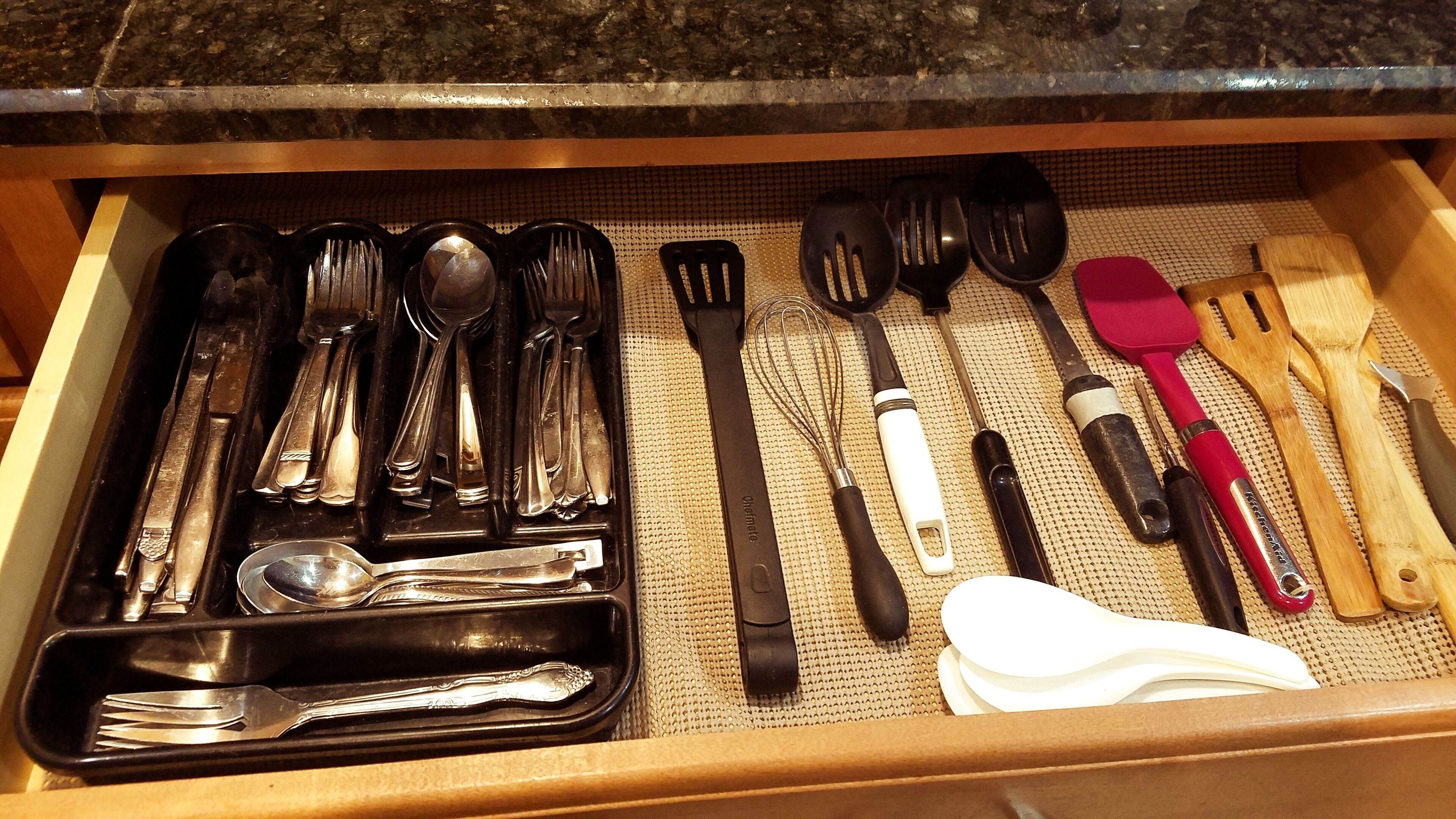 A drawer containing various kitchen utensils including forks, spoons, spatulas, and whisks.
