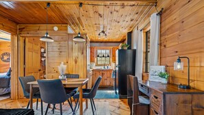 L’intérieur d’une cabane en bois comprend un coin repas, une cuisine et un bureau avec des tiroirs.