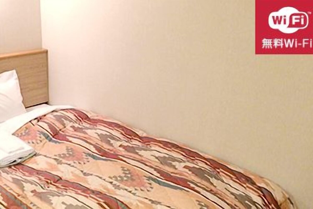 Ein Hotelzimmer mit einem Bett, einer Steuerung am Kopfteil und einem WLAN-Symbol an der Wand.