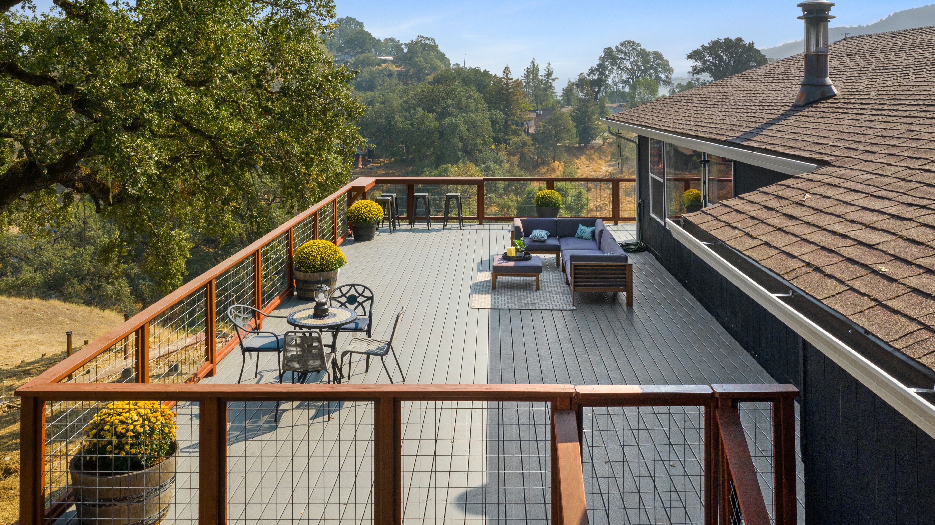 A deck with outdoor furniture, a railing, and potted plants.