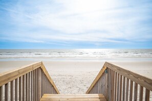 A wooden boardwalk leading to a beach with a clear sky. - Beach Therapy: Oceanfront Condo with Seasonal Community Pool (Caswell Beach)