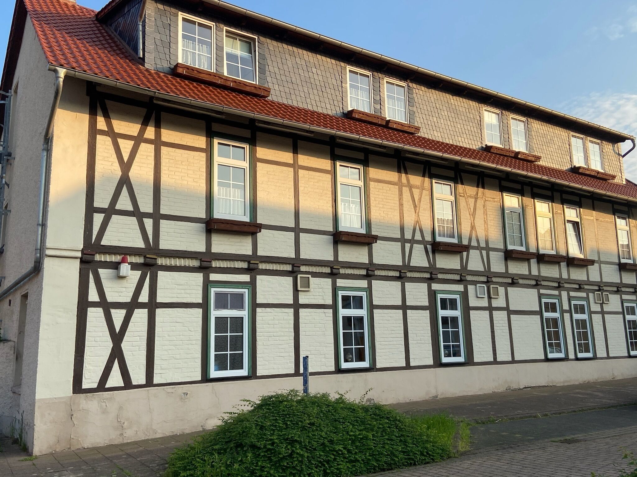 Un bâtiment traditionnel à colombages, doté de nombreuses fenêtres et d’un toit recouvert de tuiles rouges.