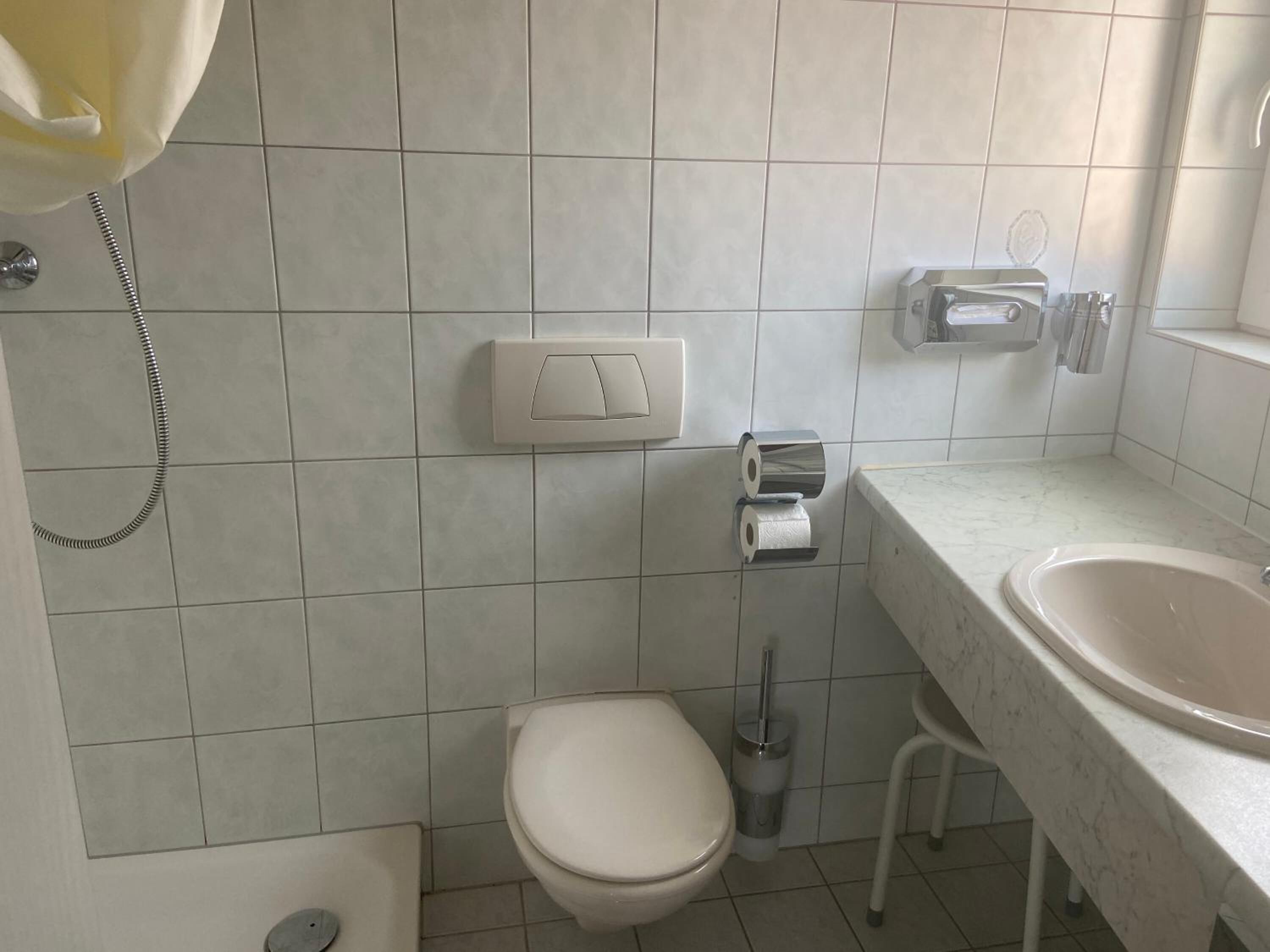Un baño con inodoro, bidé, secador de manos y lavamanos.