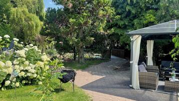 Een tuin met een kiosk, een pad en een vogel.