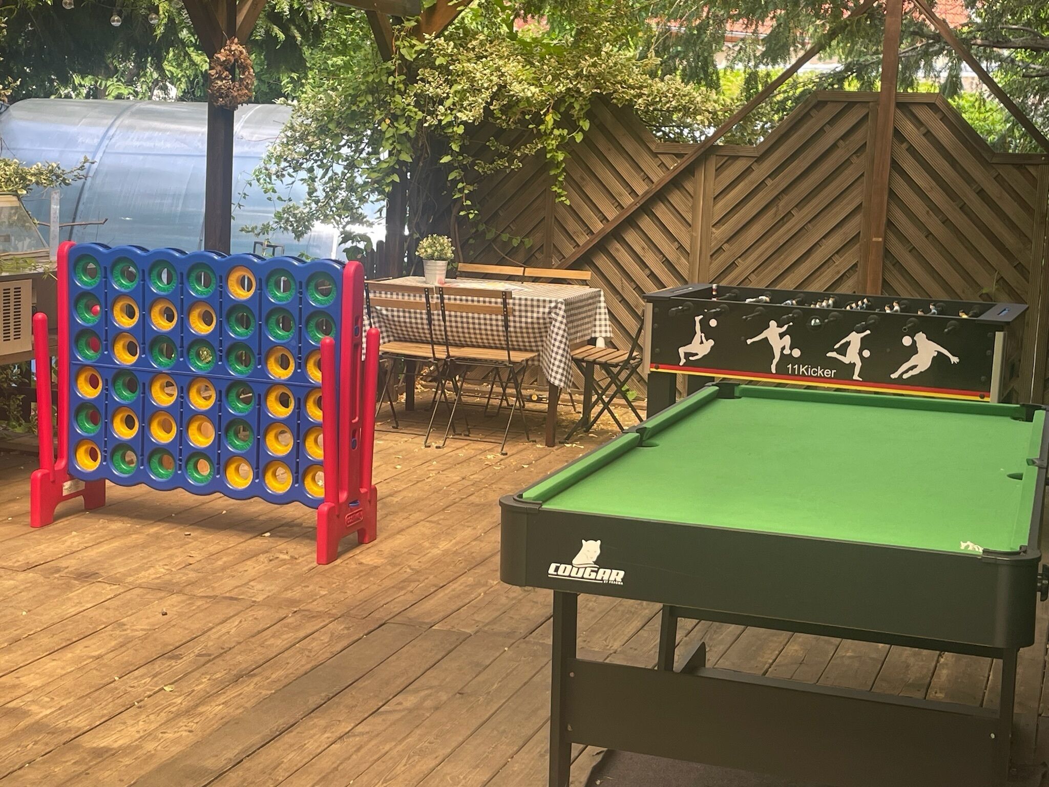 A pool table with a Cougar logo and a 11Kicker table tennis table with a checkered tablecloth.