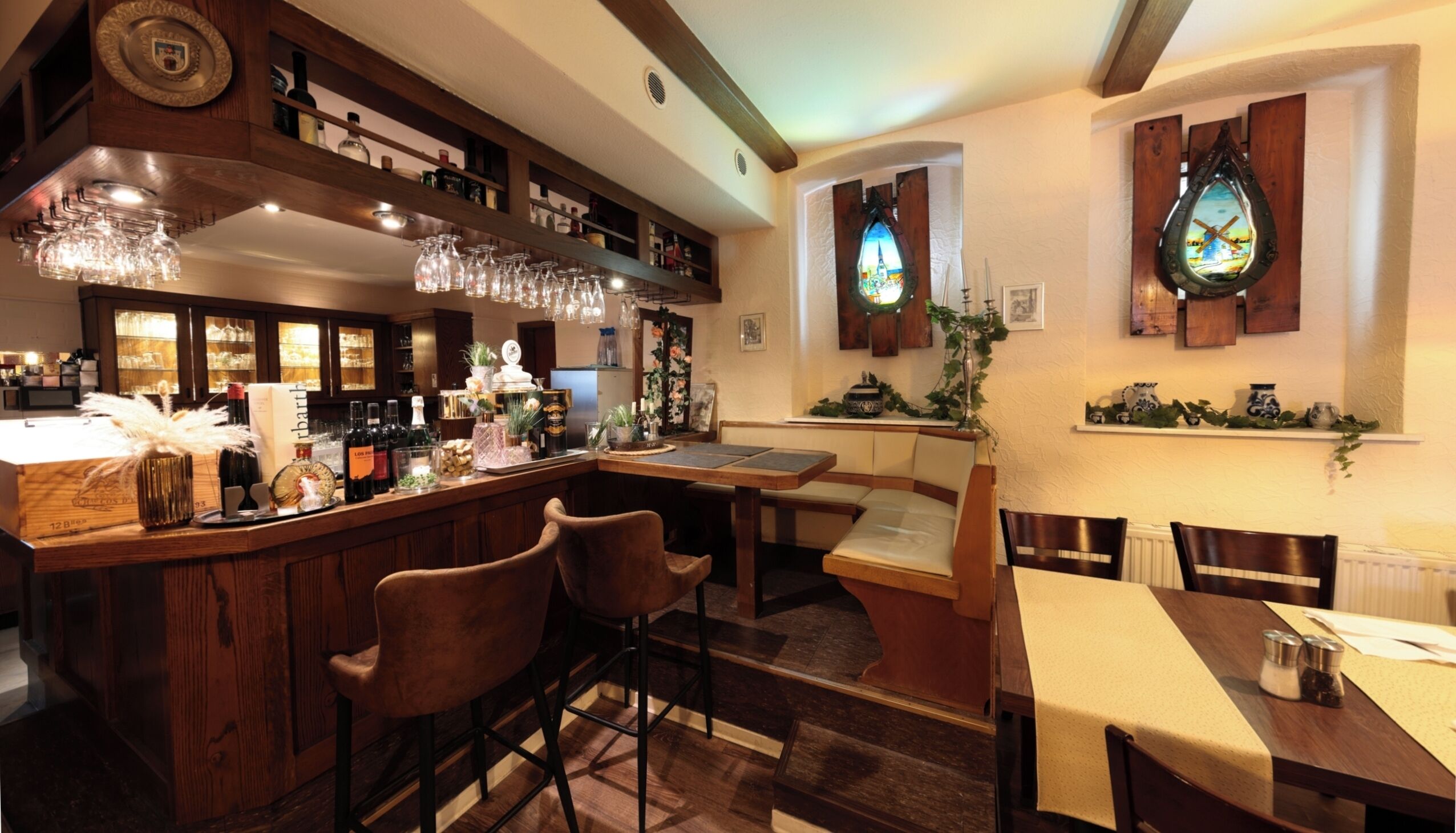 Uma área de bar com mobiliário de madeira, um balcão com garrafas e um espelho decorativo.