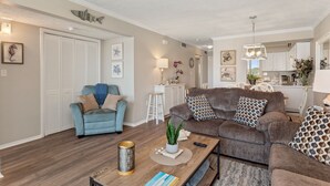 Una sala de estar con un sillón azul, un sofá marrón y una mesita de centro con objetos decorativos.