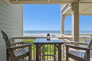 Terraza de madera con mesa y sillas con vistas a una playa.
