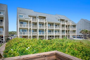 Un hotel de varios pisos con balcones, un paseo techado y un jardín ajardinado.