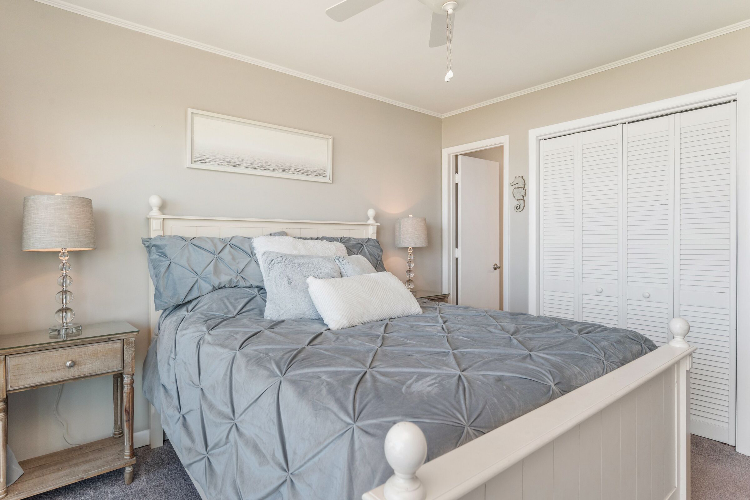 A bedroom with a bed, nightstands, a ceiling fan, a door, and a closet.