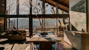 A spacious living area with a large dining table, comfortable seating, and a view of the outdoors.
