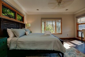 A bedroom with a bed, a nightstand, a lamp, a window, and a ceiling fan. - Falling Water Lodge | Gorgeous 5BR Mountaintop Lodge (Burnsville)