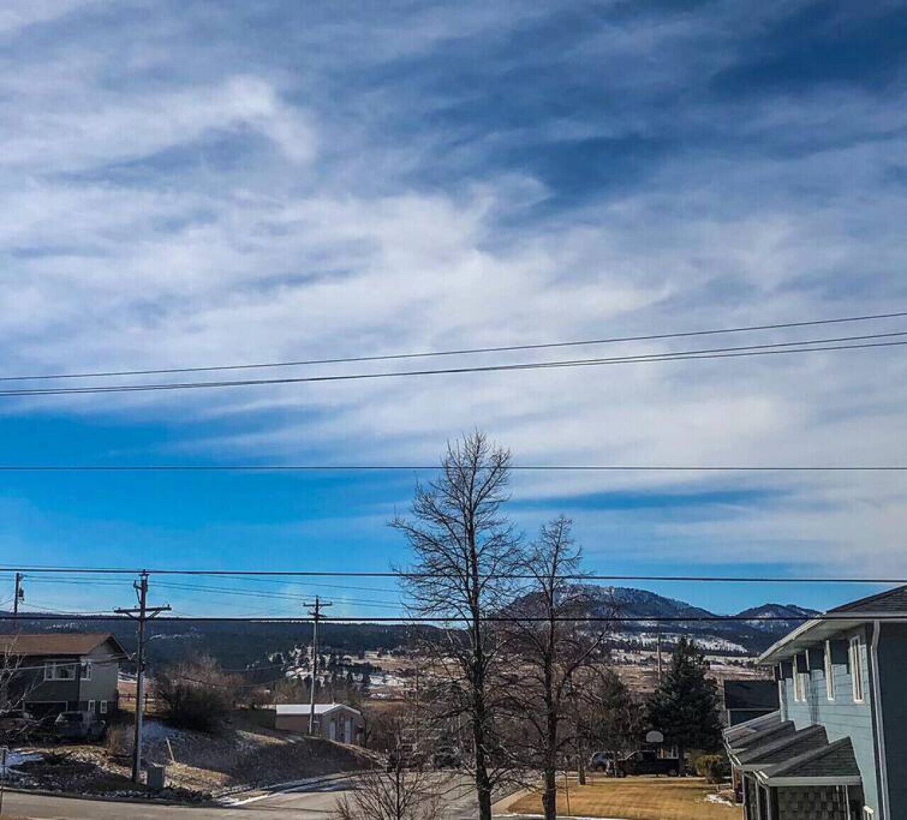 A residential area with houses, power lines, and a mountain in the background.