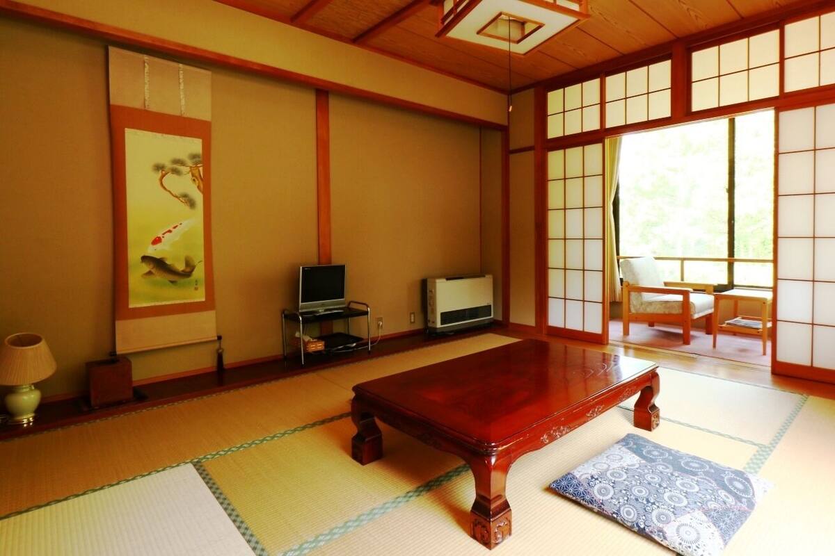Egy hagyományos japán szoba, tatami szőnyeggel, egy faasztallal, egy televízióval és tolóajtókkal.
