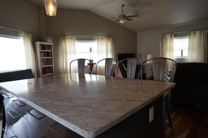 Enjoy cooking in this well-equipped kitchen with a large granite countertop, bookshelf, and ceiling fan.