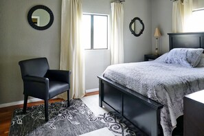 Relax in a stylish bedroom with a neatly made bed, black chair, and modern nightstand.