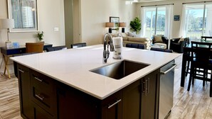 A modern kitchen with a large island, built-in appliances, and a view to the outdoors. - Golfers` Paradise. Large Townhouse By 1st Hole In Private Gated Community (Gulf Shores)
