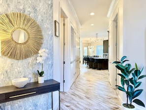 Stunning hallway leads to a spacious dining area with a long table and comfortable seating.