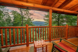 A wooden deck with a railing overlooking a forested landscape.