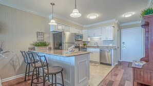 Cozinha moderna com ilha central, eletrodomésticos de aço inoxidável e iluminação pendente.