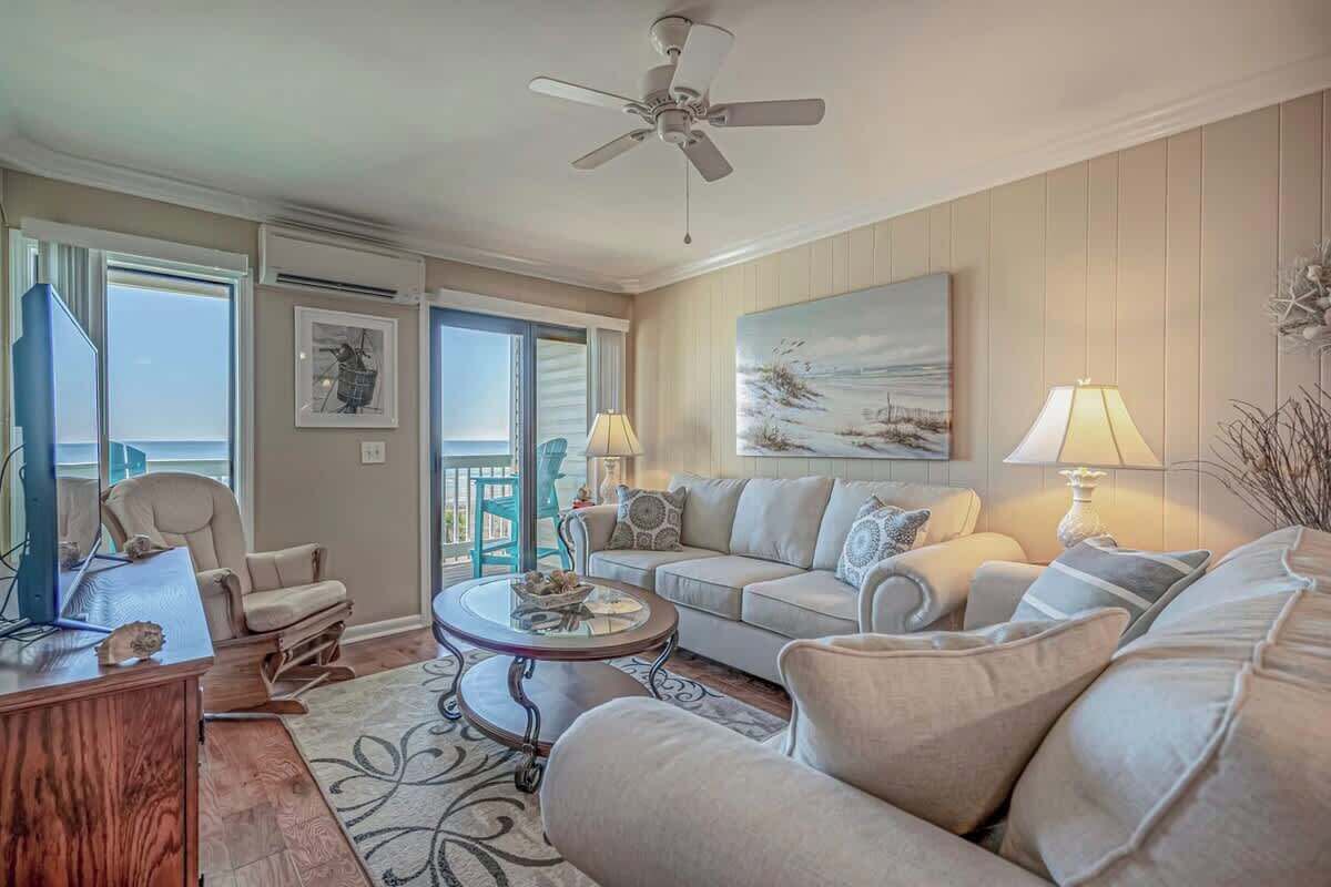 A living room with a sofa, armchairs, a coffee table, and a ceiling fan.
