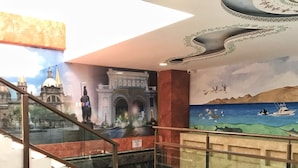 Un escalier orné d’une fresque représentant un paysage urbain et une scène maritime.
