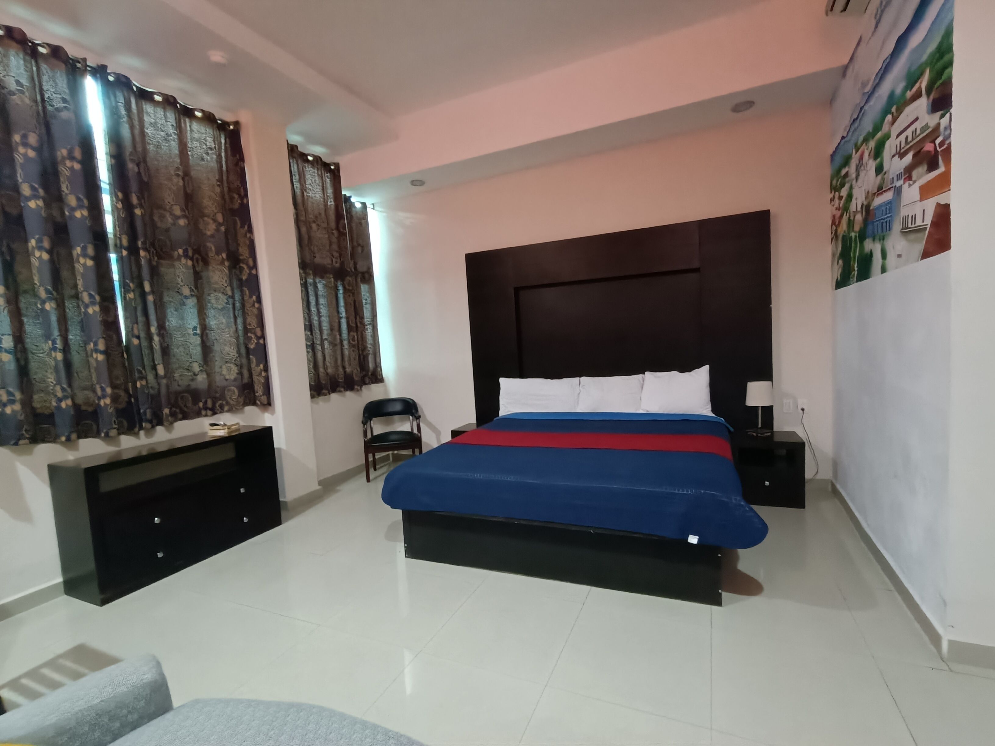 A bedroom with a bed, a chair, a TV, and a wall with a poster.