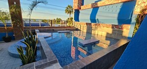 Une piscine dont le bord est recouvert de carreaux, entourée de plantes en pot et bordée d’un mur également recouvert de carreaux bleus.