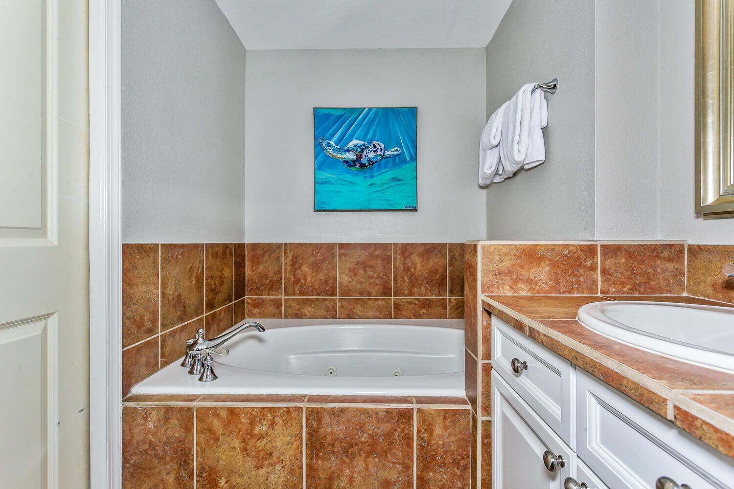 Un baño con bañera, lavamanos y toallero.