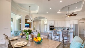 A modern kitchen with white cabinets, a central island, and a dining area with a wooden table set for four.